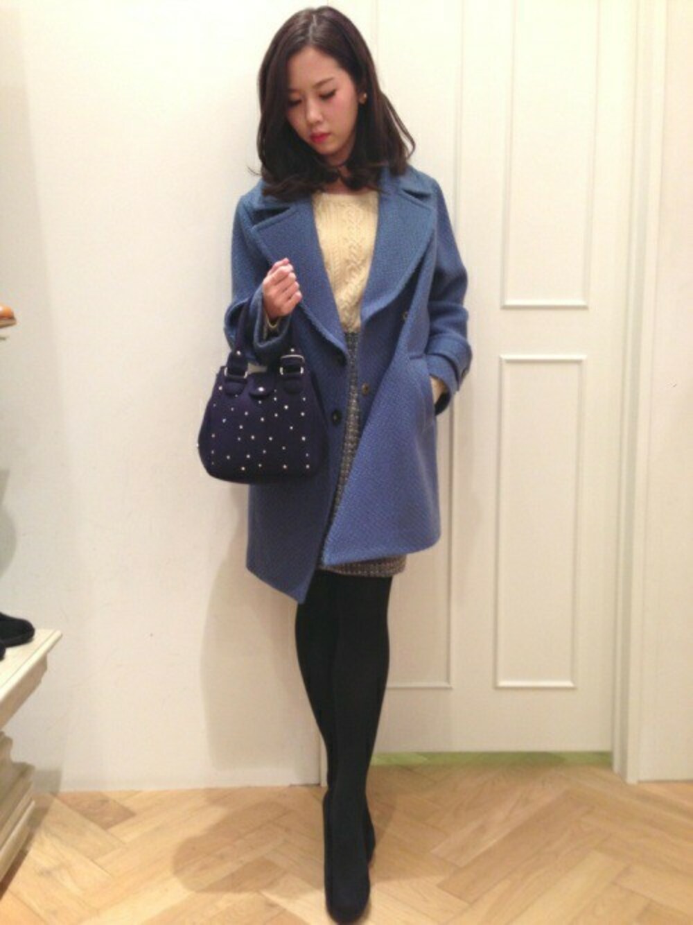ブルー系のステンカラーコート、ベージュ系のニット/セーター、グレー系のスカートを着用したレディースの冬コーディネートの1枚目の写真
