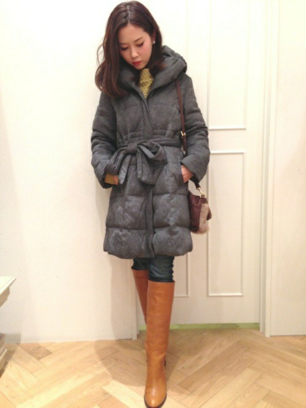 グレー系のダウンジャケット/コート、イエロー系のニット/セーター、ブルー系のデニムパンツを着用したレディースの冬コーディネートの1枚目の写真