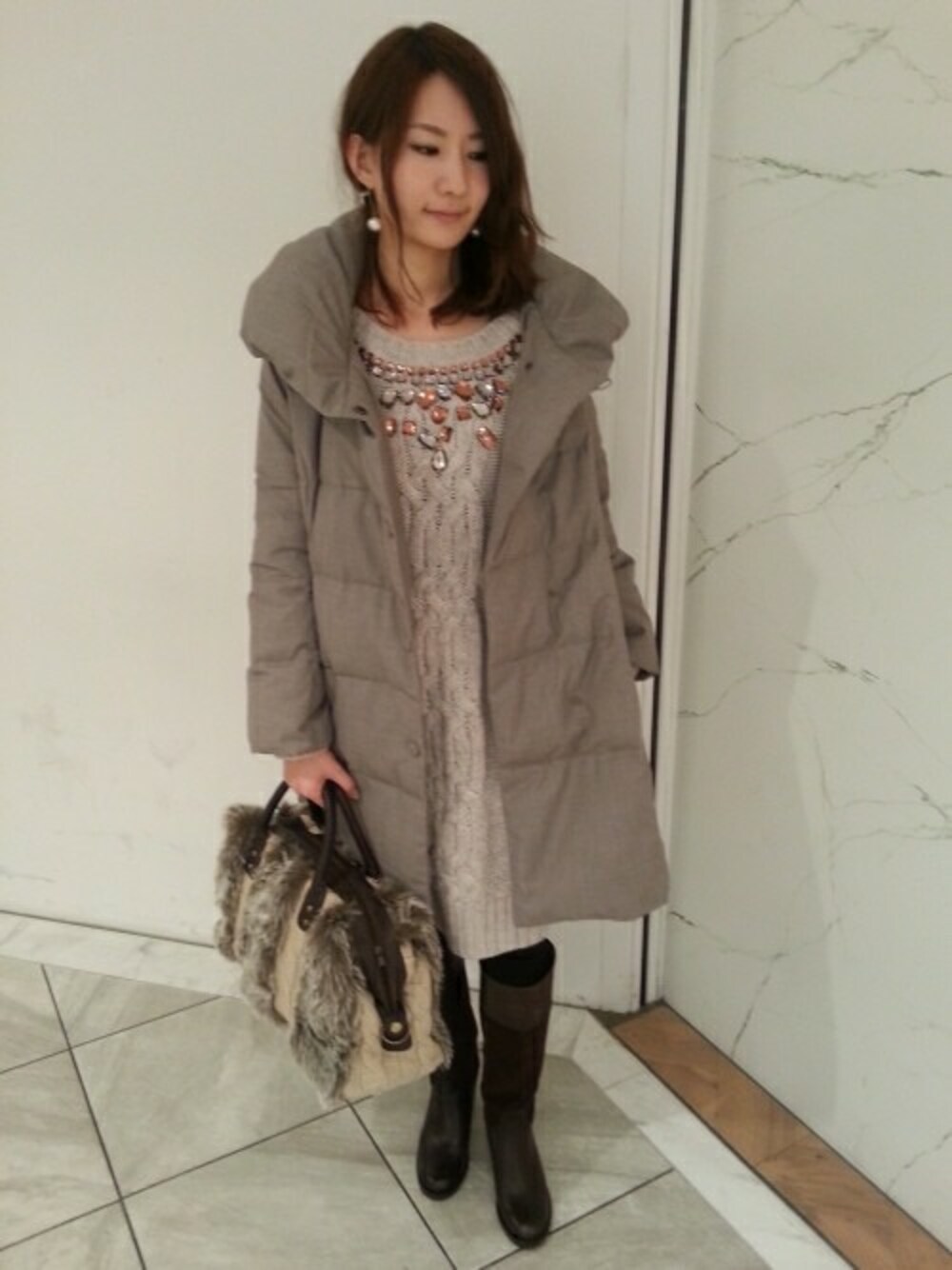 ベージュ系のダウンジャケット/コート、ベージュ系のワンピース、ベージュ系のハンドバッグを着用したレディースの冬コーディネートの1枚目の写真