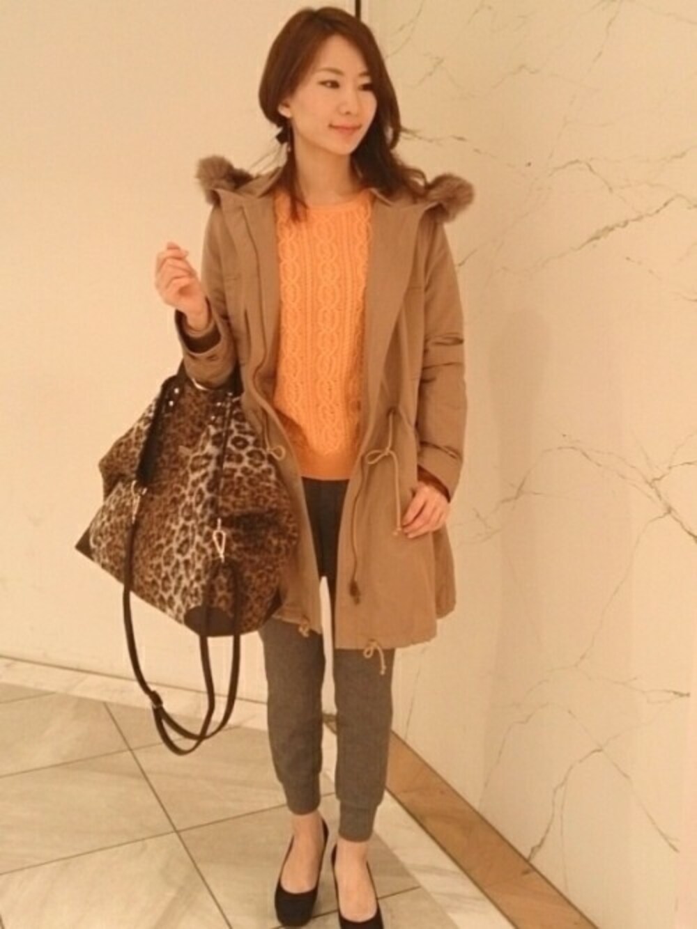 ベージュ系のモッズコート、オレンジ系のニット/セーター、グレー系のその他パンツを着用したレディースの冬コーディネートの1枚目の写真