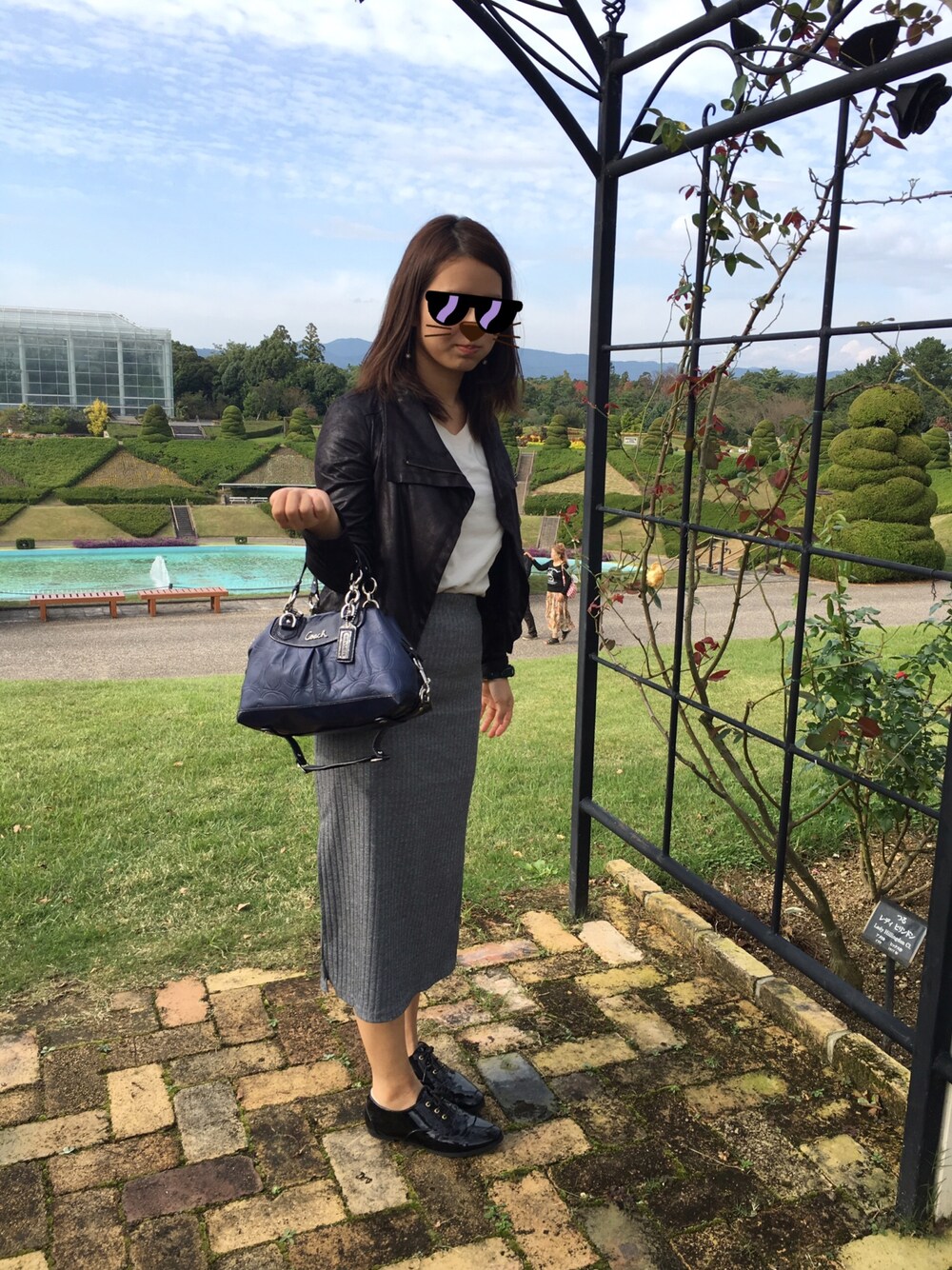 グレー系のスカート、ブルー系のハンドバッグ、ホワイト系のTシャツ/カットソーを着用したレディースの秋コーディネートの1枚目の写真