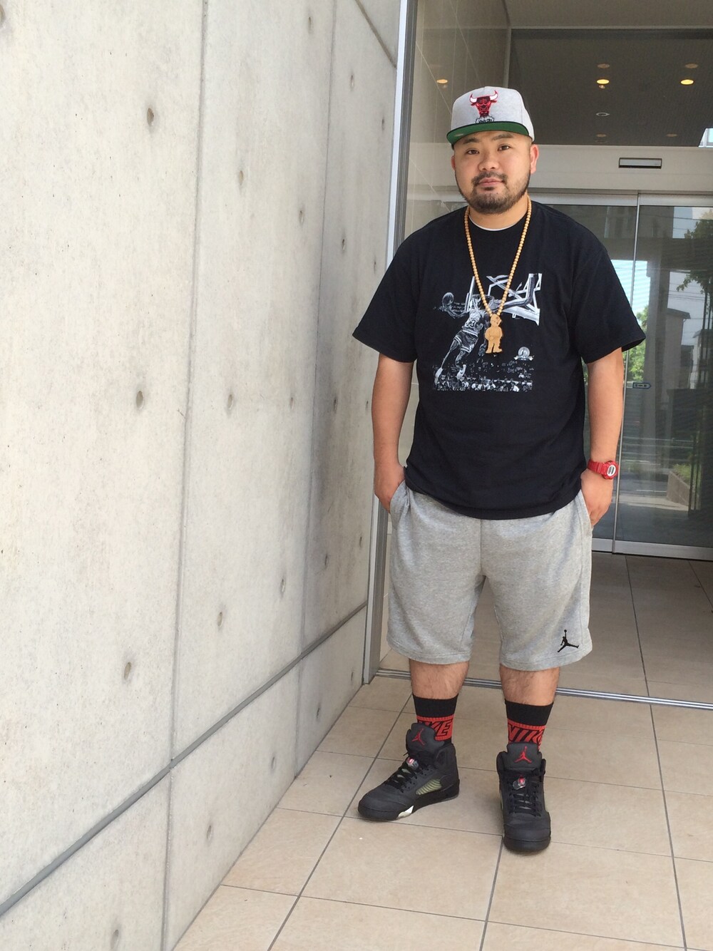 グレー系のカーゴパンツ、ブラック系のスニーカー、ブラック系のTシャツ/カットソーを着用したメンズの夏コーディネートの1枚目の写真