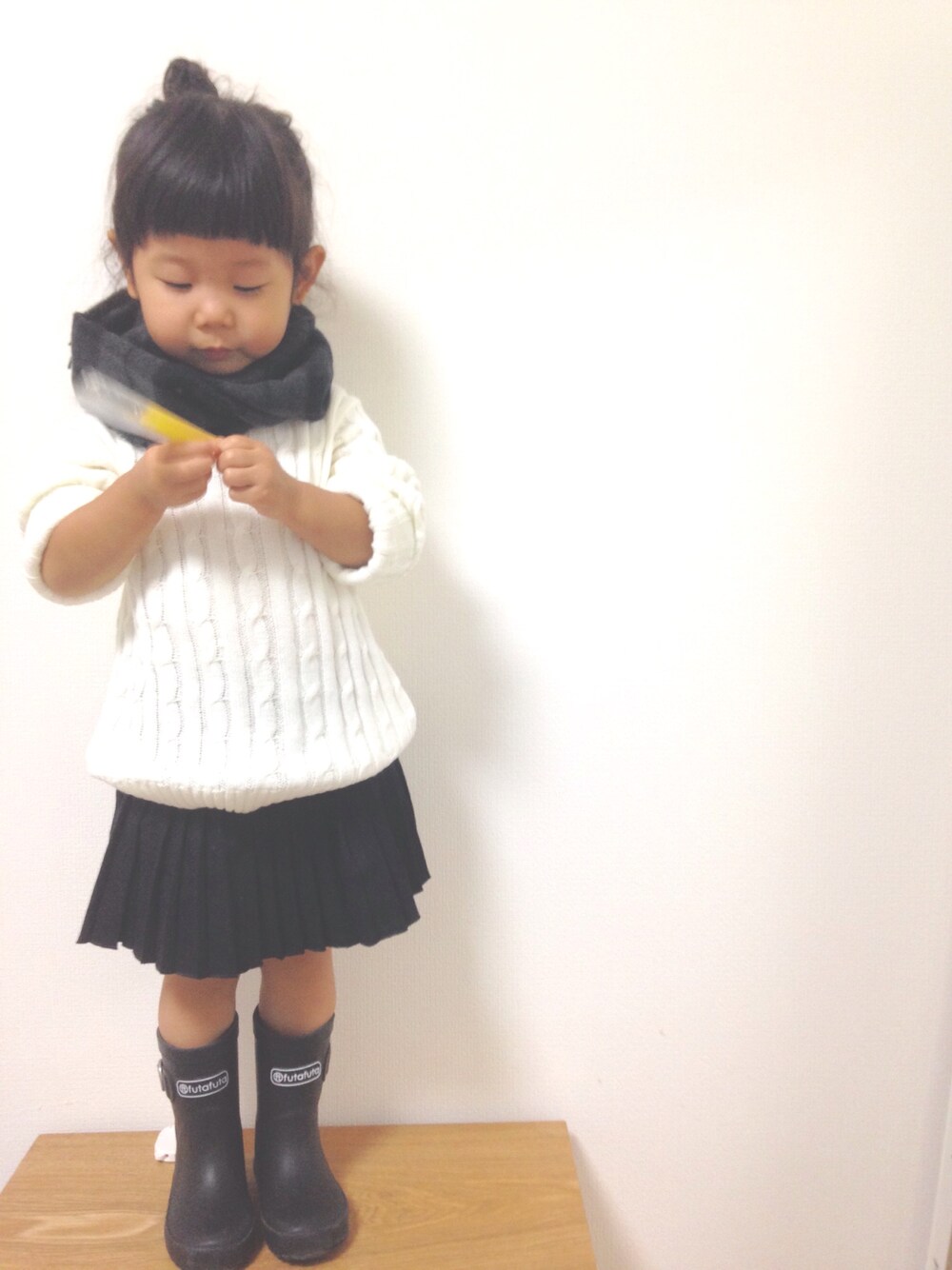ホワイト系のニット/セーター、ブラック系のスカート、ブラック系のレインシューズを着用したキッズの秋コーディネートの1枚目の写真