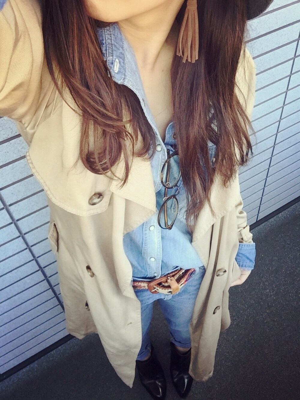 ベージュ系のトレンチコート、ブルー系のデニムパンツ、ブラック系のブーツを着用したレディースの秋コーディネートの1枚目の写真