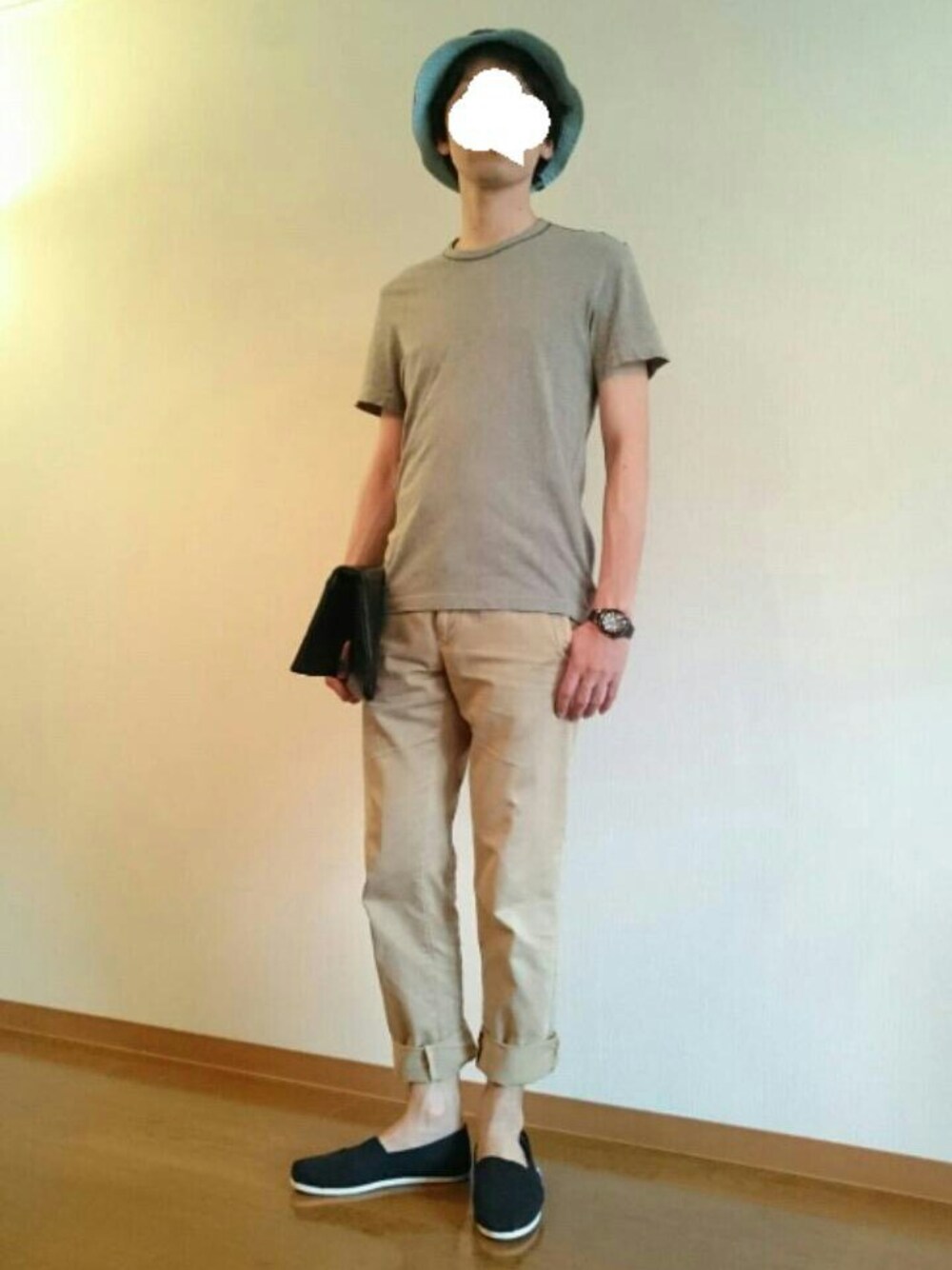 ブラック系のクラッチバッグ、ブラック系のスニーカー、ブラウン系のチノパンツを着用したメンズの春コーディネートの1枚目の写真