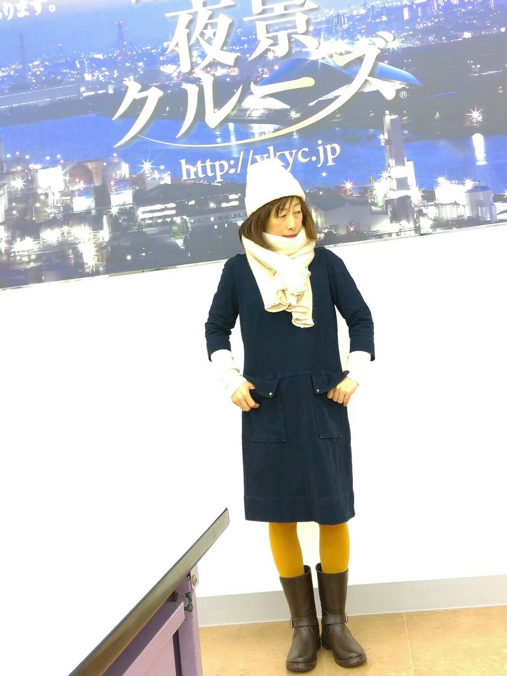 ブルー系のワンピース、ホワイト系のニット/セーター、ベージュ系のストール/ショールを着用したレディースの春コーディネートの1枚目の写真