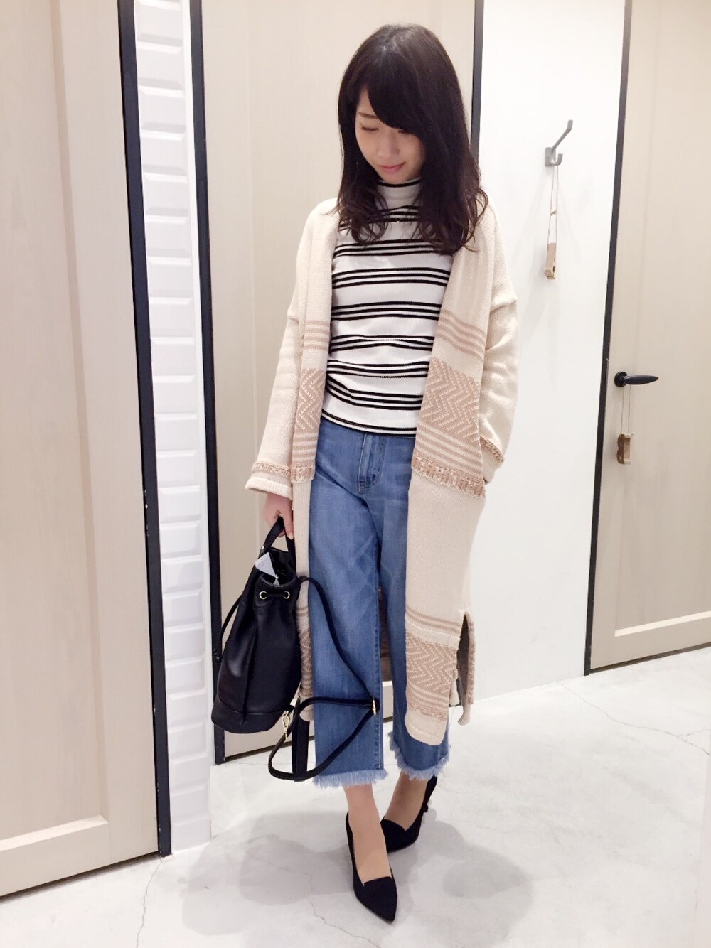 ブルー系のデニムパンツ、ホワイト系のトップス、ブラック系のバックパック/リュックを着用したレディースの冬コーディネートの1枚目の写真