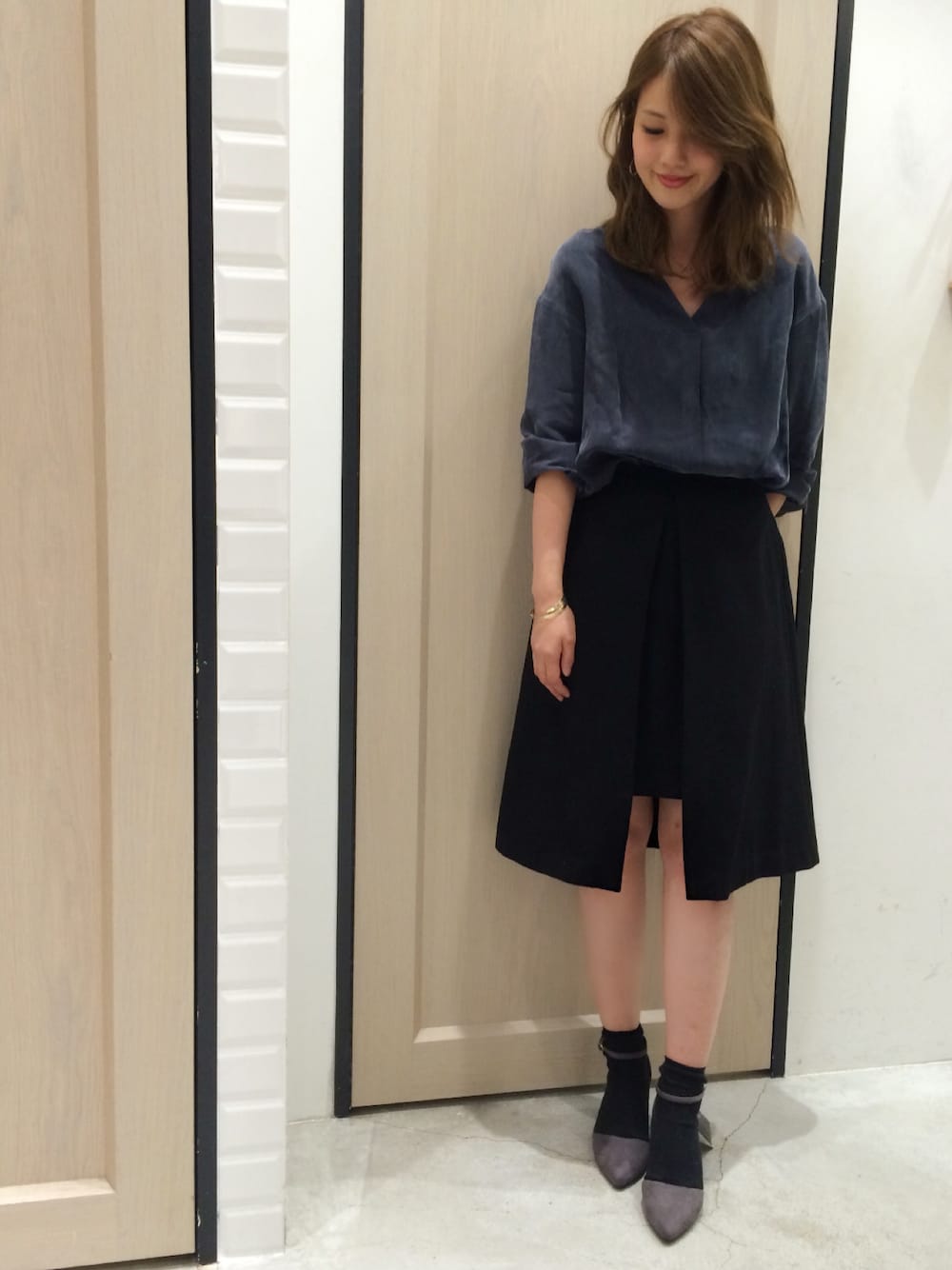 ブルー系のトップス、ブラック系のスカート、グレー系のその他シューズを着用したレディースの秋コーディネートの1枚目の写真