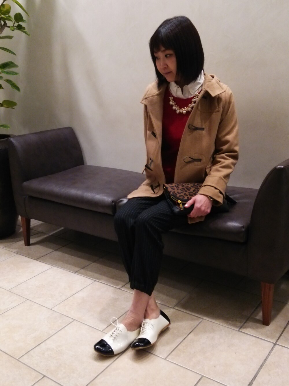 イエロー系のダッフルコート、ホワイト系のシャツ/ブラウス、レッド系のニット/セーターを着用したレディースの冬コーディネートの1枚目の写真