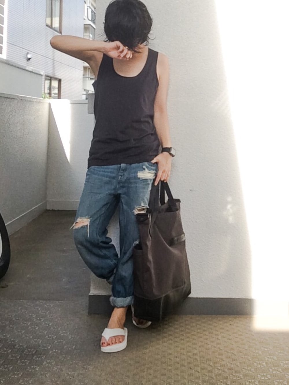 グレー系のタンクトップ、ブルー系のデニムパンツ、グレー系のトートバッグを着用したレディースの夏コーディネートの1枚目の写真