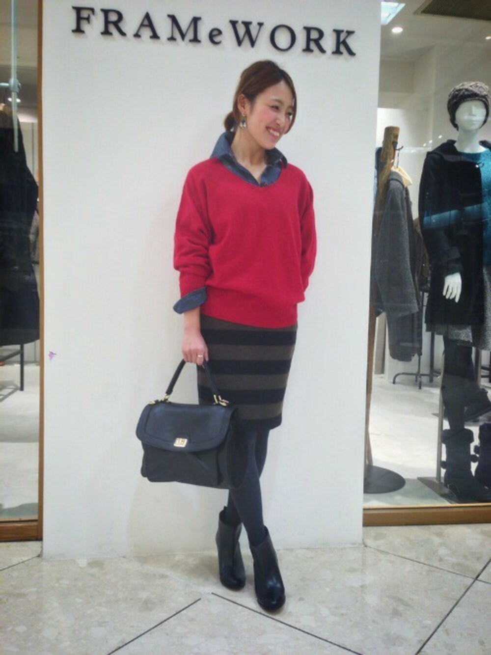 ブラウン系のスカート、ブラック系のショルダーバッグ、レッド系のニット/セーターを着用したレディースの冬コーディネートの1枚目の写真