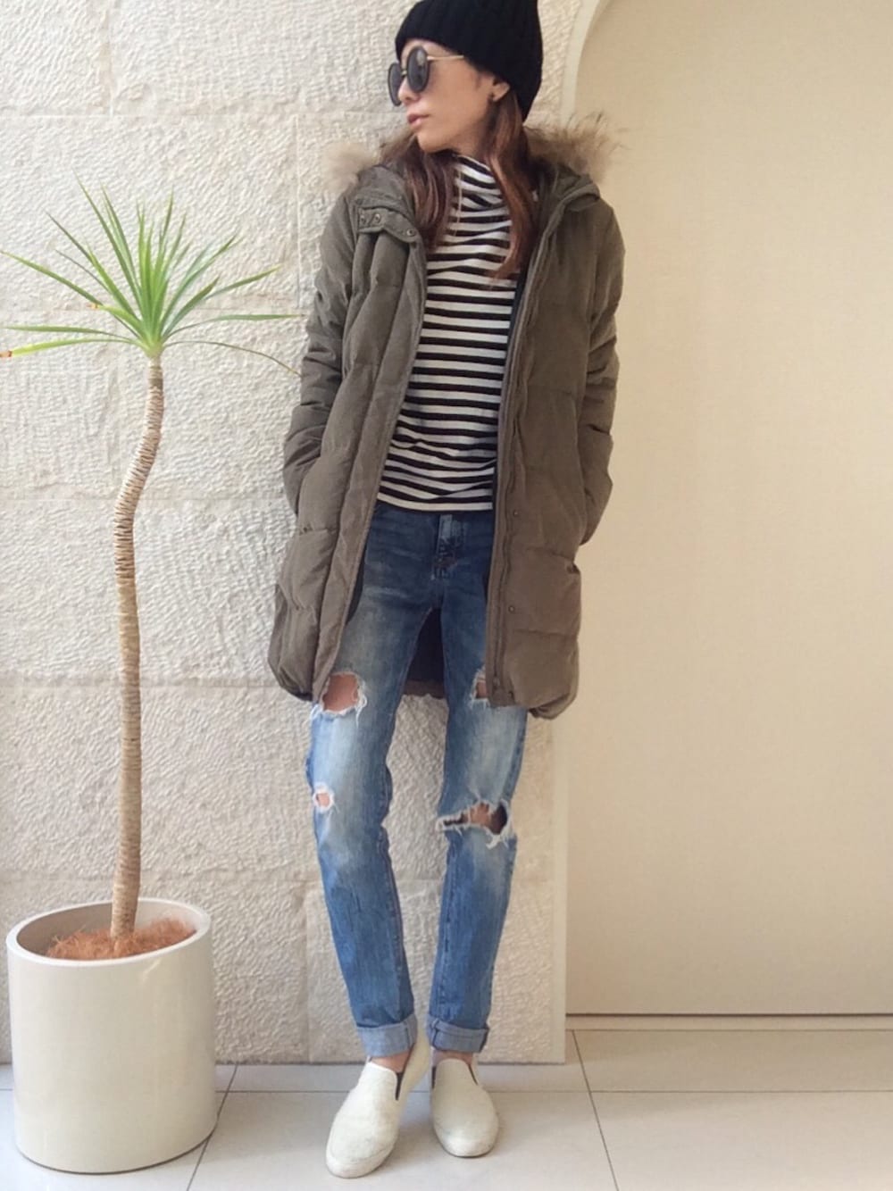 グリーン系のダウンジャケット/コート、ブラック系のトップス、ブルー系のデニムパンツを着用したレディースの冬コーディネートの1枚目の写真