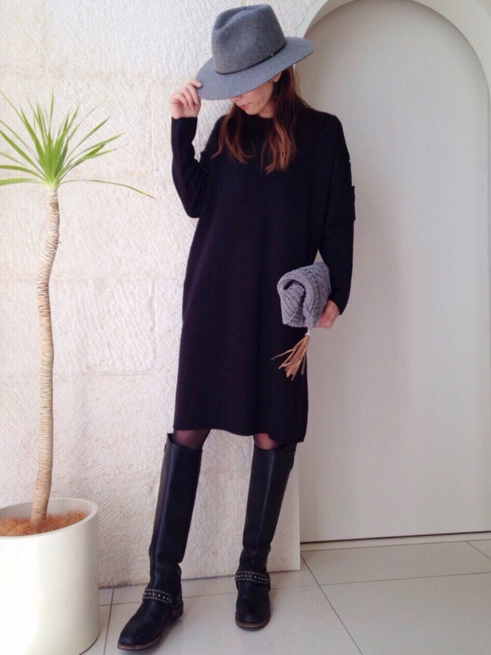 ブラック系のワンピース、グレー系のクラッチバッグ、ブラック系のブーツを着用したレディースの冬コーディネートの1枚目の写真