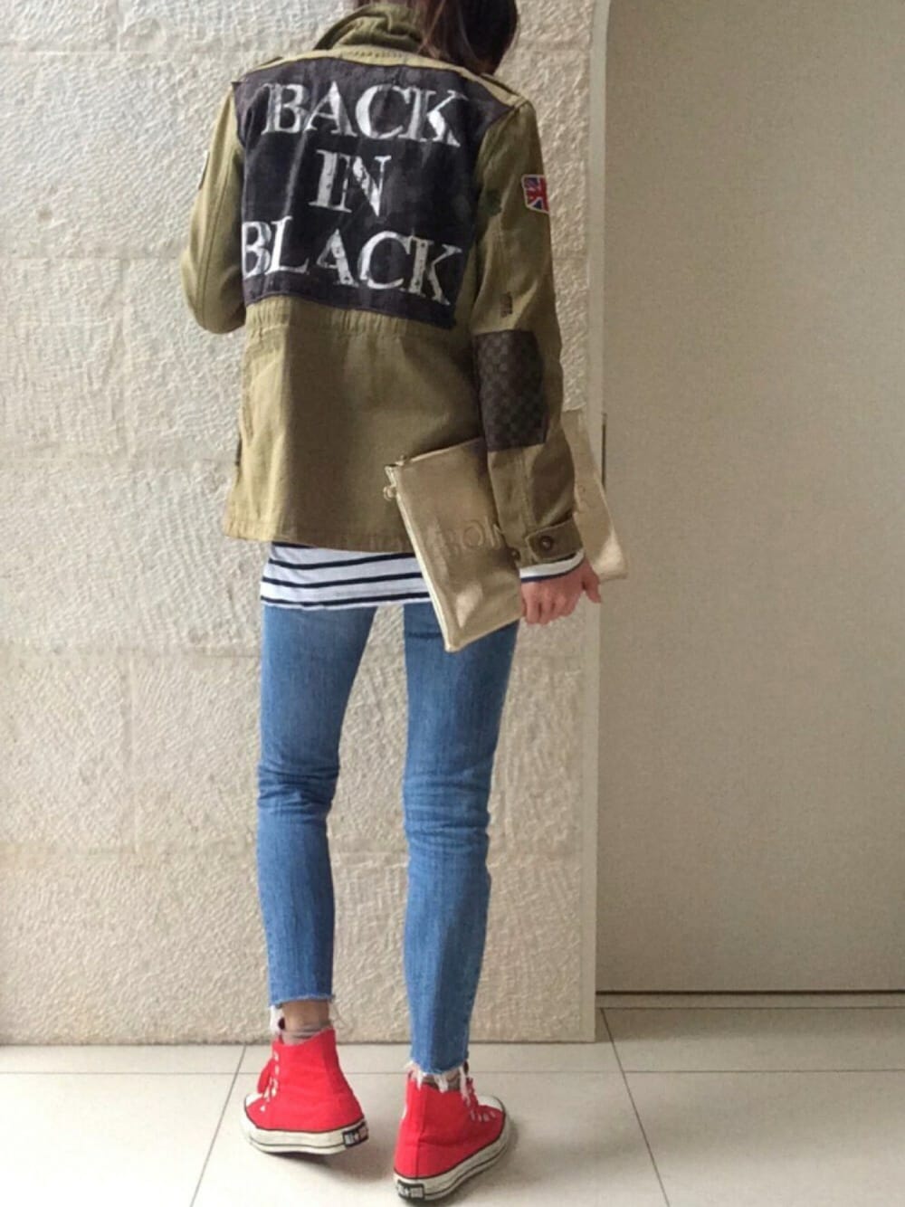 グリーン系のミリタリージャケット、ブルー系のデニムパンツ、レッド系のスニーカーを着用したレディースの春コーディネートの1枚目の写真