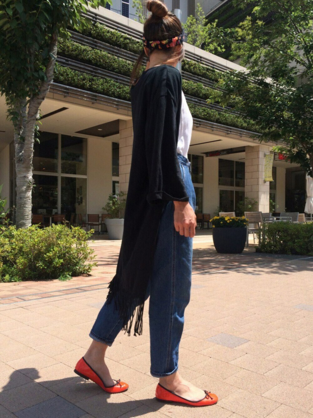 ブルー系のデニムパンツ、オレンジ系のバレエシューズ、ブラック系のカーディガン/ボレロを着用したレディースの夏コーディネートの1枚目の写真