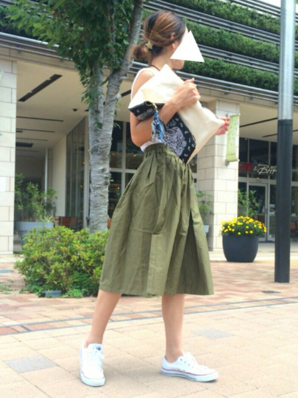 ホワイト系のスニーカー、ホワイト系のタンクトップ、ブラック系のクラッチバッグを着用したレディースの夏コーディネートの1枚目の写真