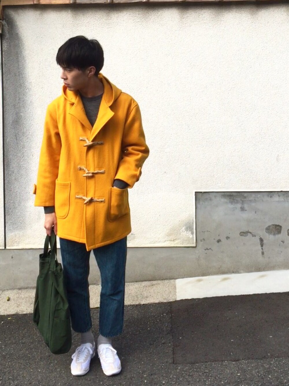 イエロー系のダッフルコート、グレー系のスウェット、ブルー系のデニムパンツを着用したメンズの冬コーディネートの1枚目の写真