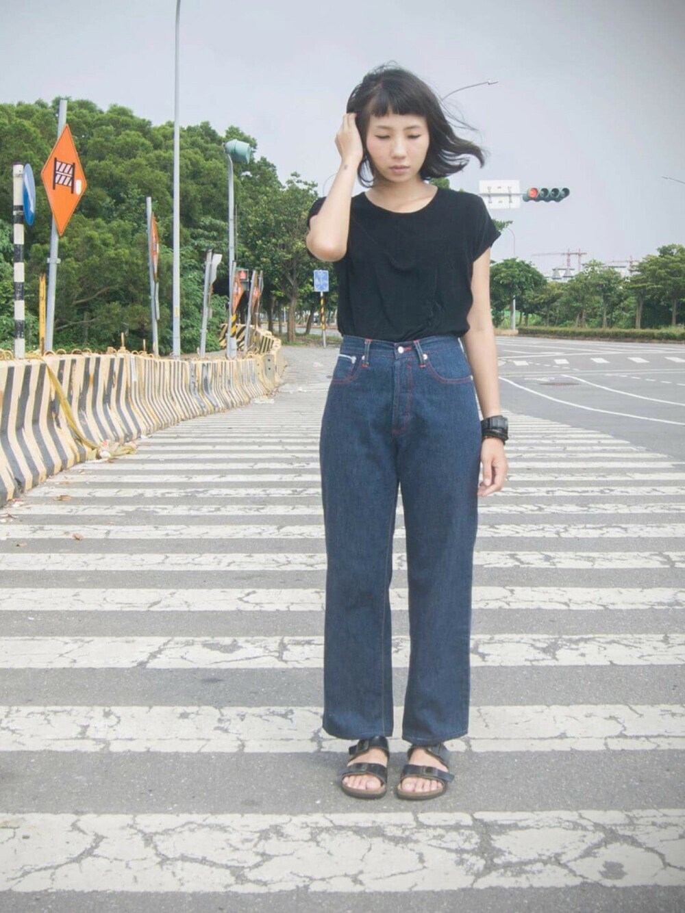 ブラック系のビーチサンダル、ブラック系のTシャツ/カットソー、ブルー系のデニムパンツを着用したレディースの夏コーディネートの1枚目の写真