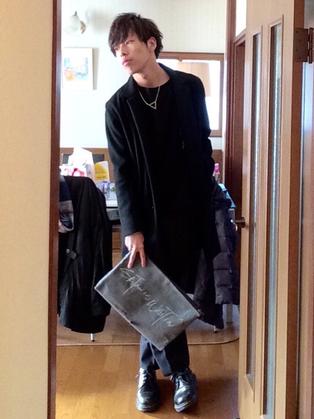 ブラック系のステンカラーコート、ブラック系のTシャツ/カットソー、ブラック系のスラックスを着用したメンズの冬コーディネートの1枚目の写真