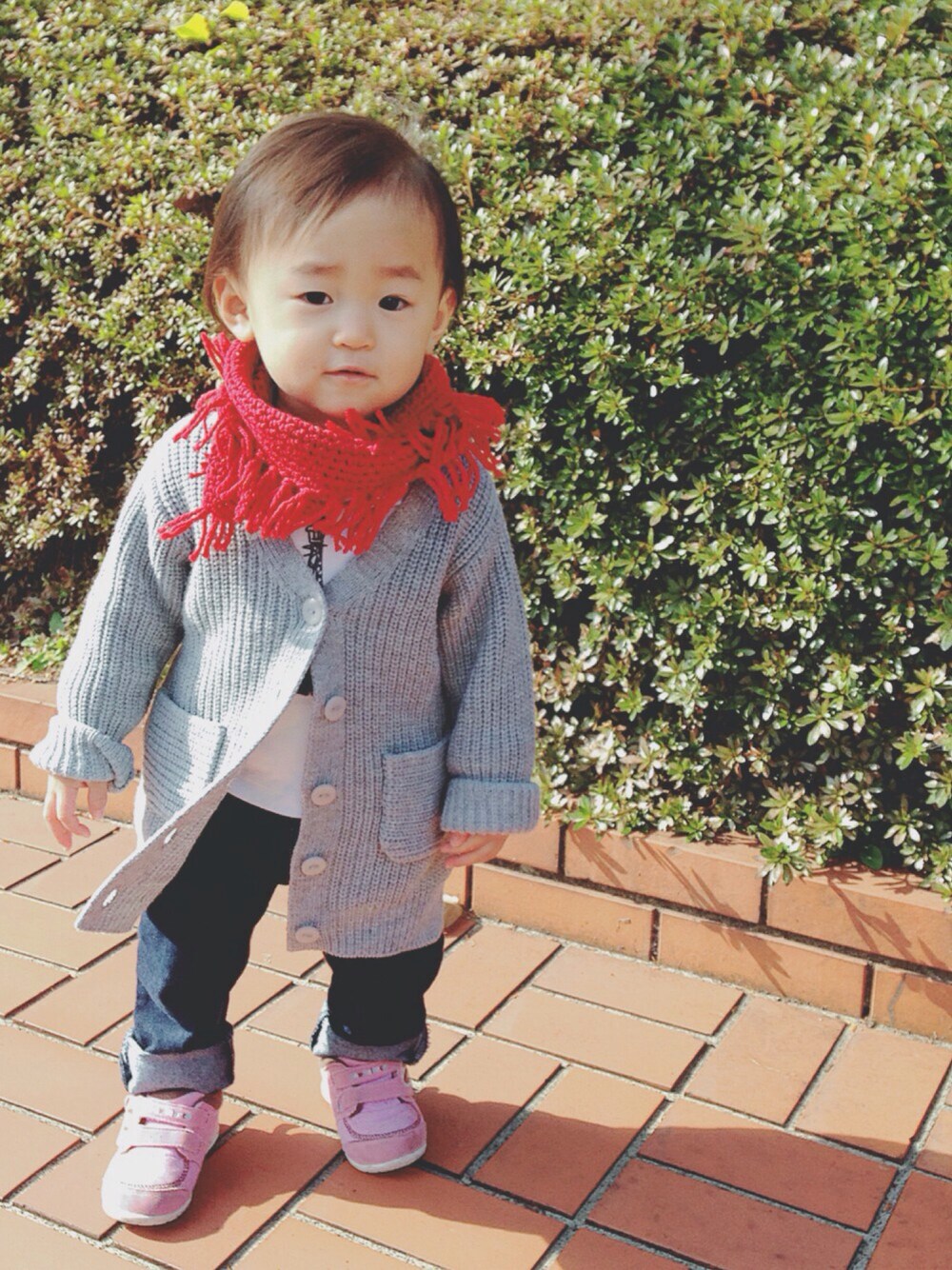 グレー系のニット/セーター、ブルー系のデニムパンツ、ピンク系のスニーカーを着用したキッズの冬コーディネートの1枚目の写真