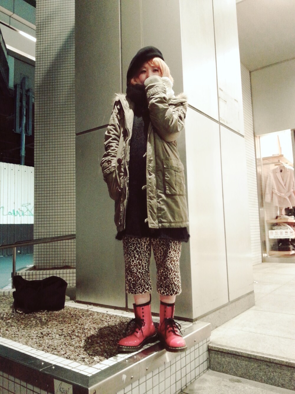 レッド系のブーツ、ブラック系のトップス、グリーン系のモッズコートを着用したレディースの冬コーディネートの1枚目の写真