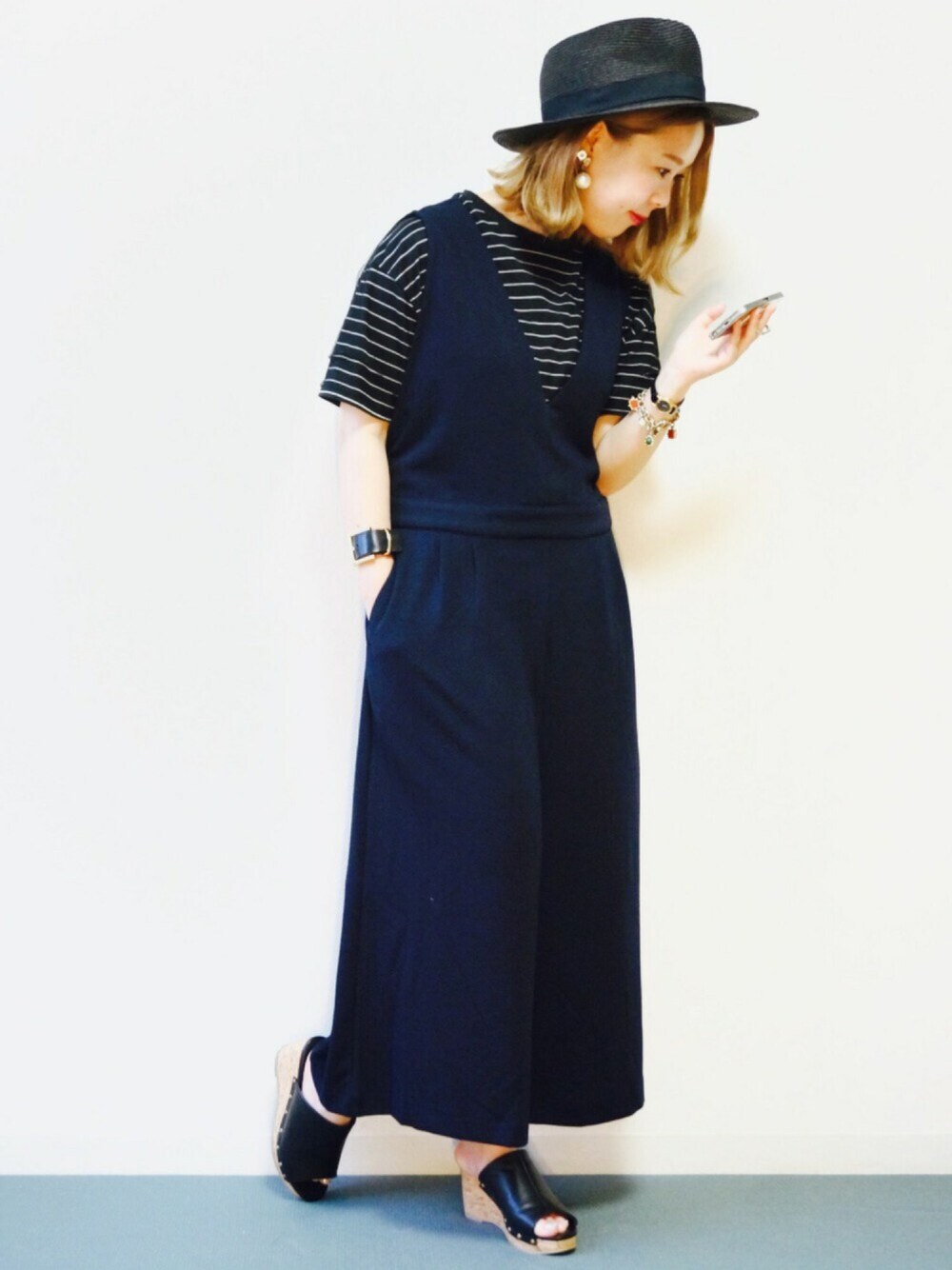 ブルー系のつなぎ/オールインワン、ブラック系のアナログ腕時計、ゴールド系のピアス(両耳用)を着用したレディースの夏コーディネートの1枚目の写真