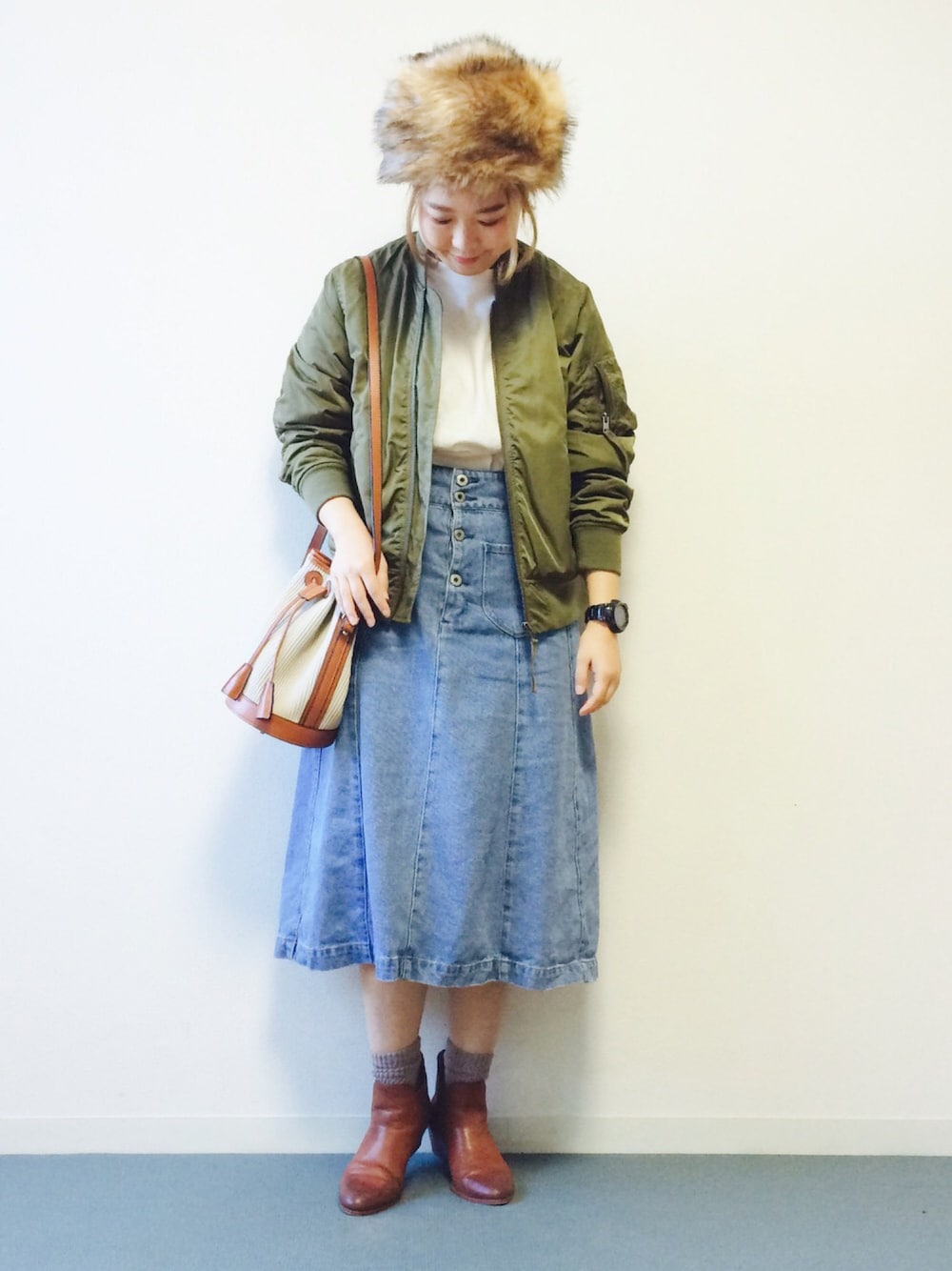 グリーン系のMA-1、ブルー系のデニムスカート、ブラウン系のブーツを着用したレディースの秋コーディネートの1枚目の写真