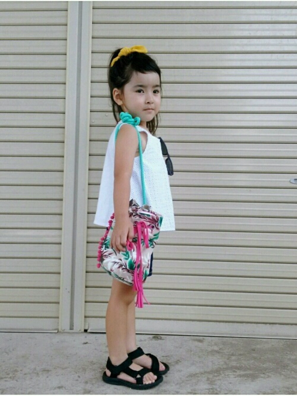 ベージュ系のショルダーバッグ、ホワイト系のトップス、ブルー系のパンツを着用したキッズの夏コーディネートの1枚目の写真