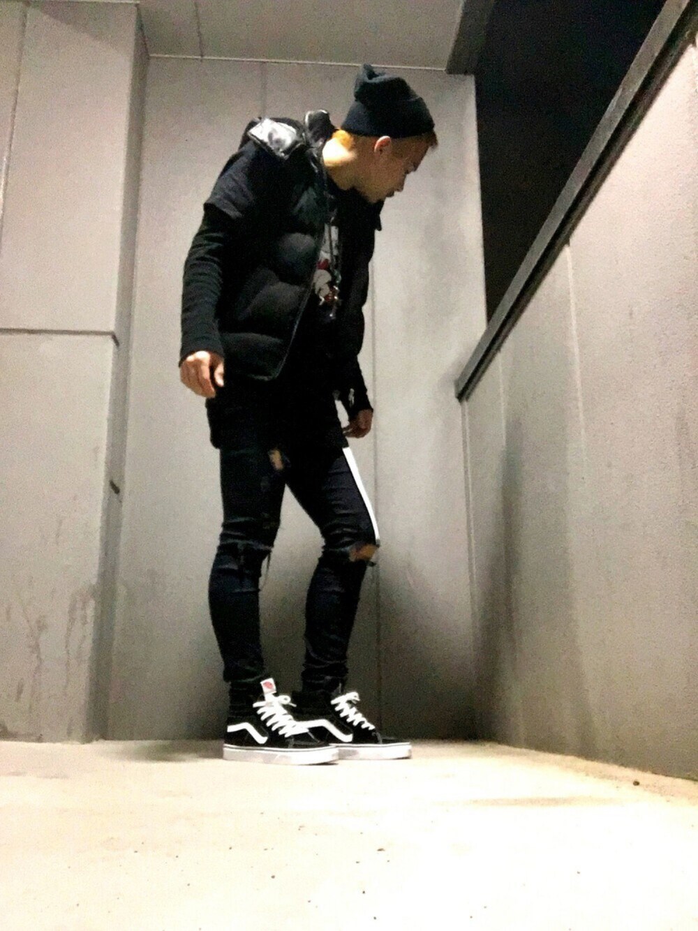 ブラック系のダウンベスト、ブラック系のTシャツ/カットソー、ブラック系のデニムパンツを着用したメンズの秋コーディネートの1枚目の写真