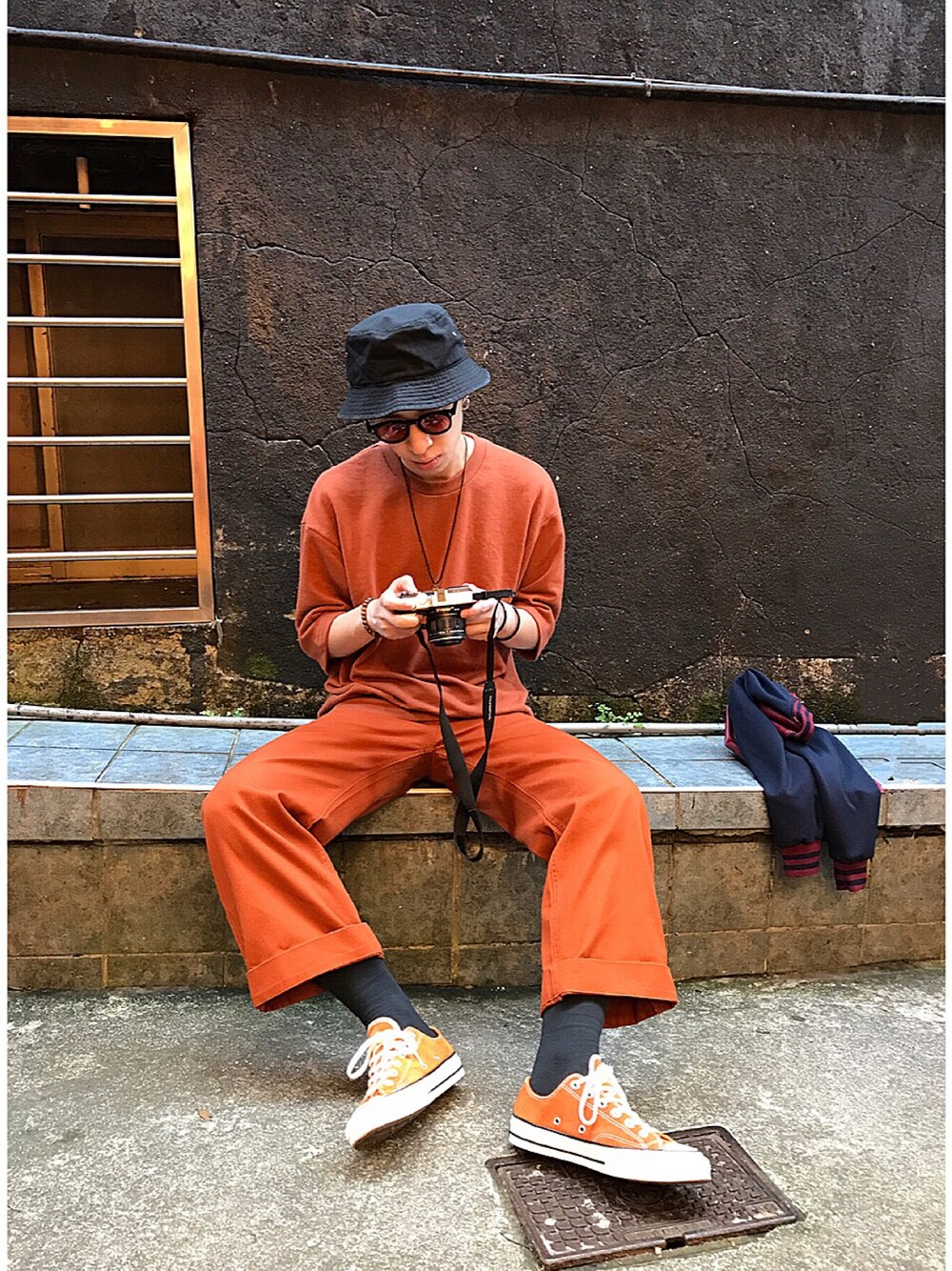 オレンジ系のスニーカー、ブラック系のメガネを着用したメンズの秋コーディネートの1枚目の写真
