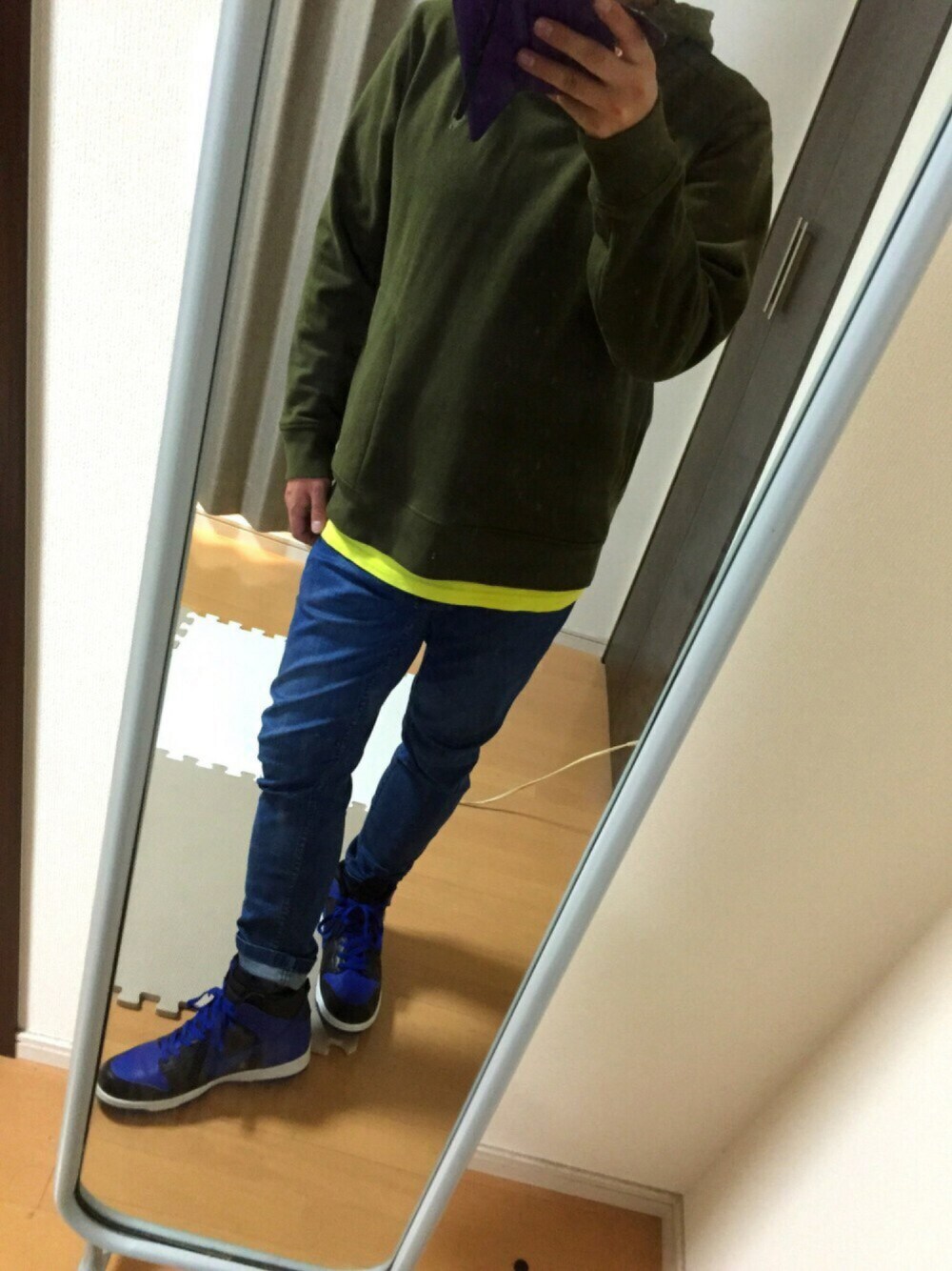 グリーン系のパーカー、イエロー系のTシャツ/カットソー、ブルー系のデニムパンツを着用したメンズの秋コーディネートの1枚目の写真