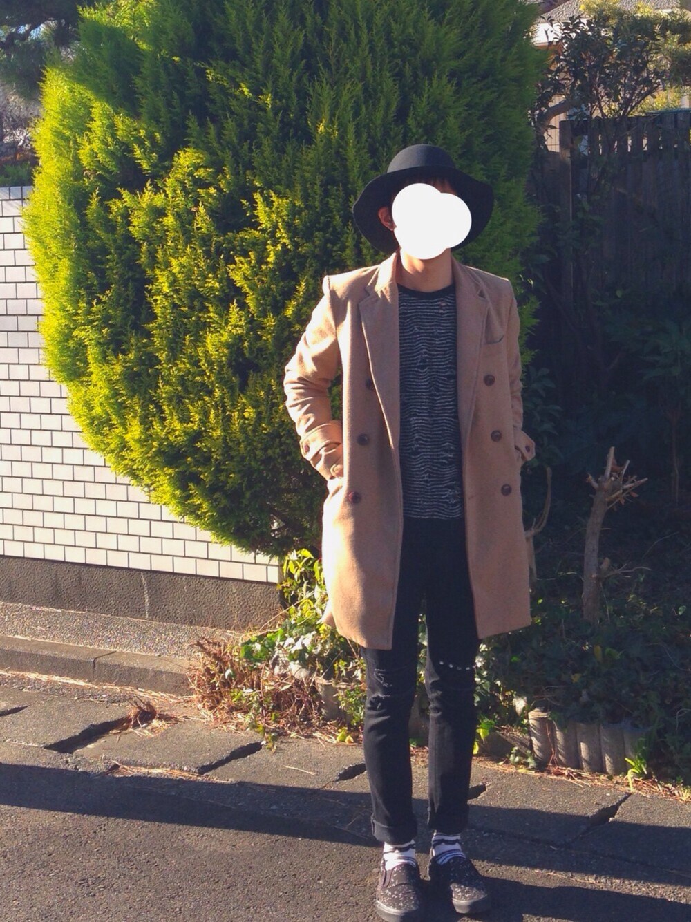 ブラック系のデニムパンツ、イエロー系のチェスターコート、ブラック系のニット/セーターを着用したメンズの冬コーディネートの1枚目の写真