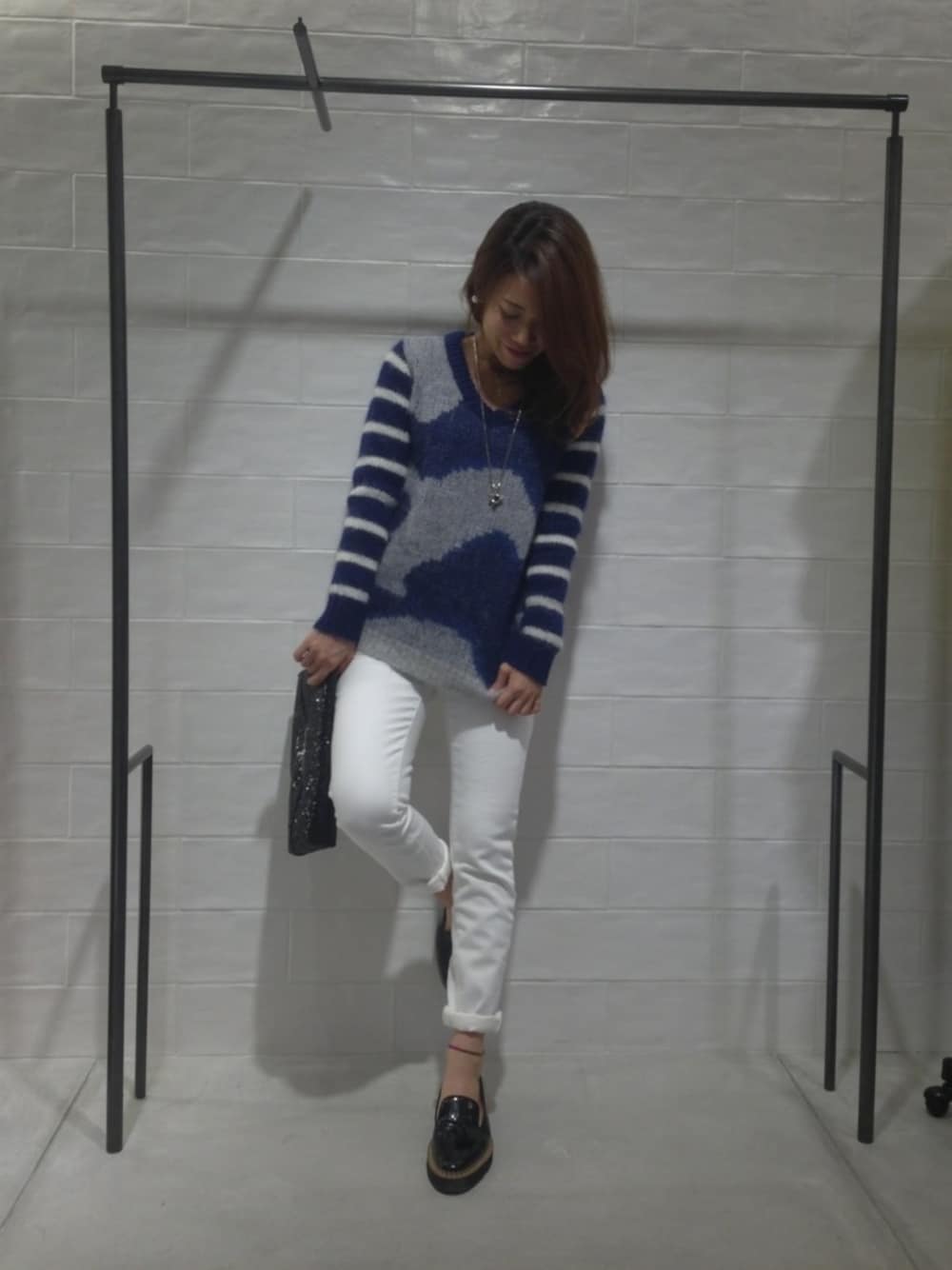 ブルー系のニット/セーター、ホワイト系のその他パンツ、ブラック系のクラッチバッグを着用したレディースの冬コーディネートの1枚目の写真