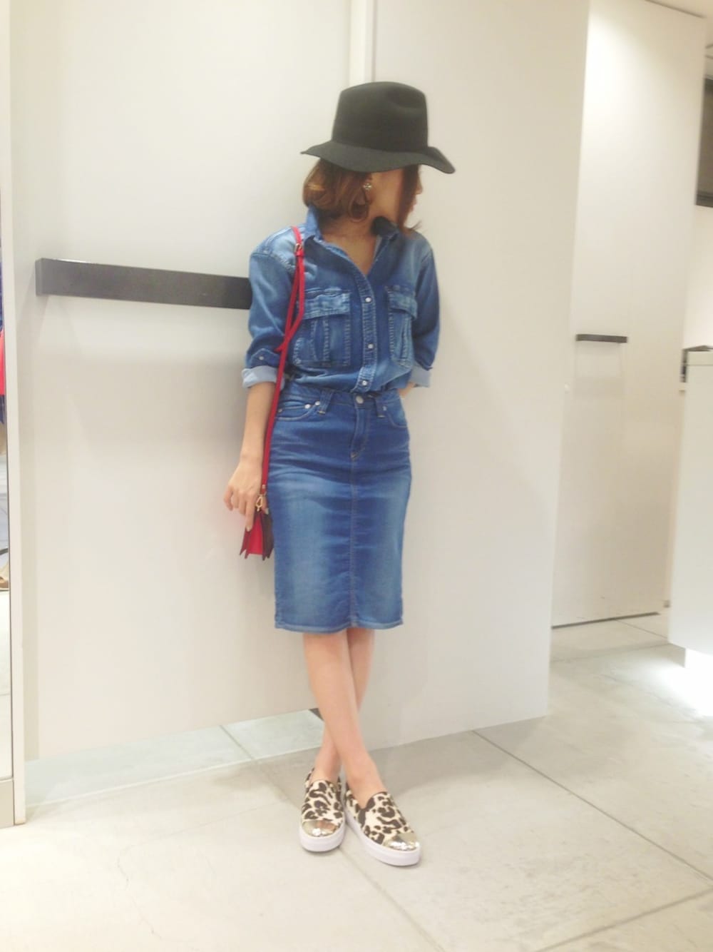 ブルー系のシャツ/ブラウス、ブルー系のデニムスカート、レッド系のショルダーバッグを着用したレディースの春コーディネートの1枚目の写真