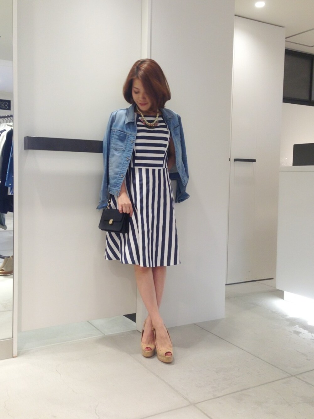 ブルー系のワンピース、ベージュ系のサンダル、ブルー系のデニムジャケットを着用したレディースの春コーディネートの1枚目の写真