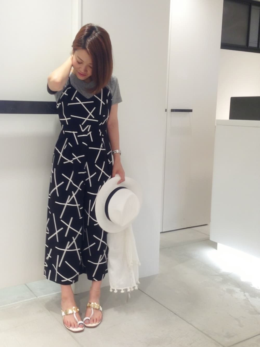 グレー系のTシャツ/カットソー、ホワイト系のサンダル、ブラック系のサロペット/オーバーオールを着用したレディースの夏コーディネートの1枚目の写真