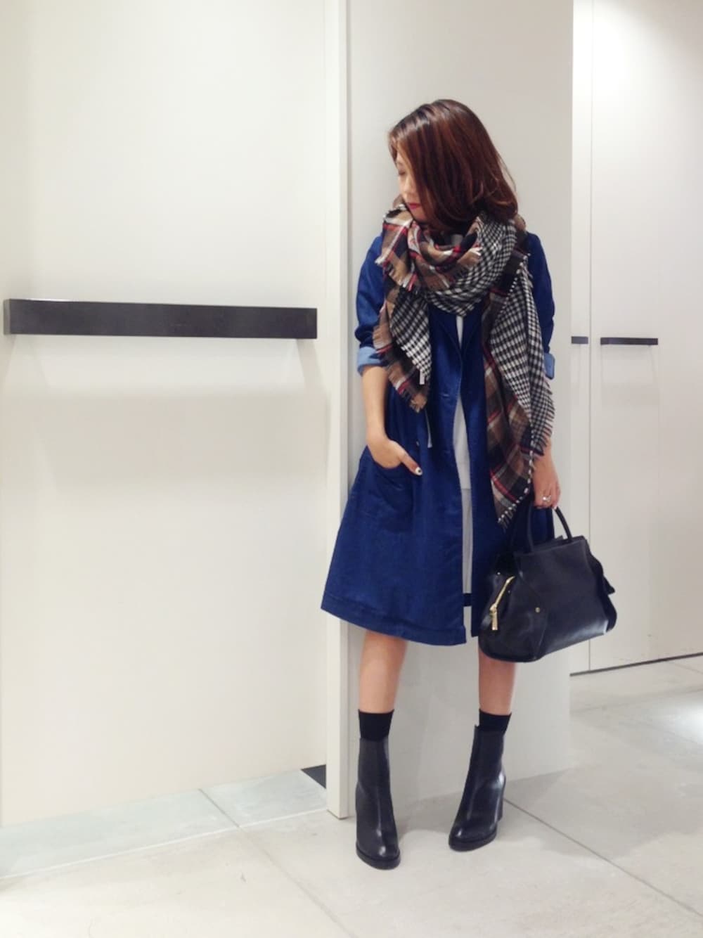 ブルー系のトレンチコート、ブラック系のトートバッグ、ブラウン系のストール/ショールを着用したレディースの秋コーディネートの1枚目の写真
