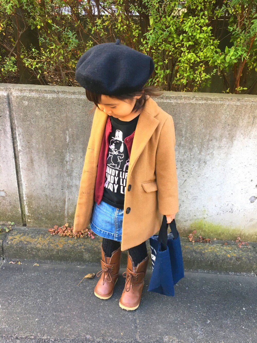 イエロー系のチェスターコート、ブラック系のTシャツ/カットソー、ブラウン系のブーツを着用したキッズの秋コーディネートの1枚目の写真