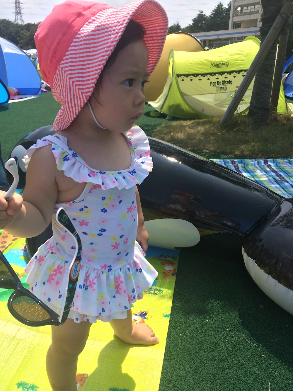 ピンク系の帽子、ブラック系のサングラスを着用したキッズの夏コーディネートの1枚目の写真