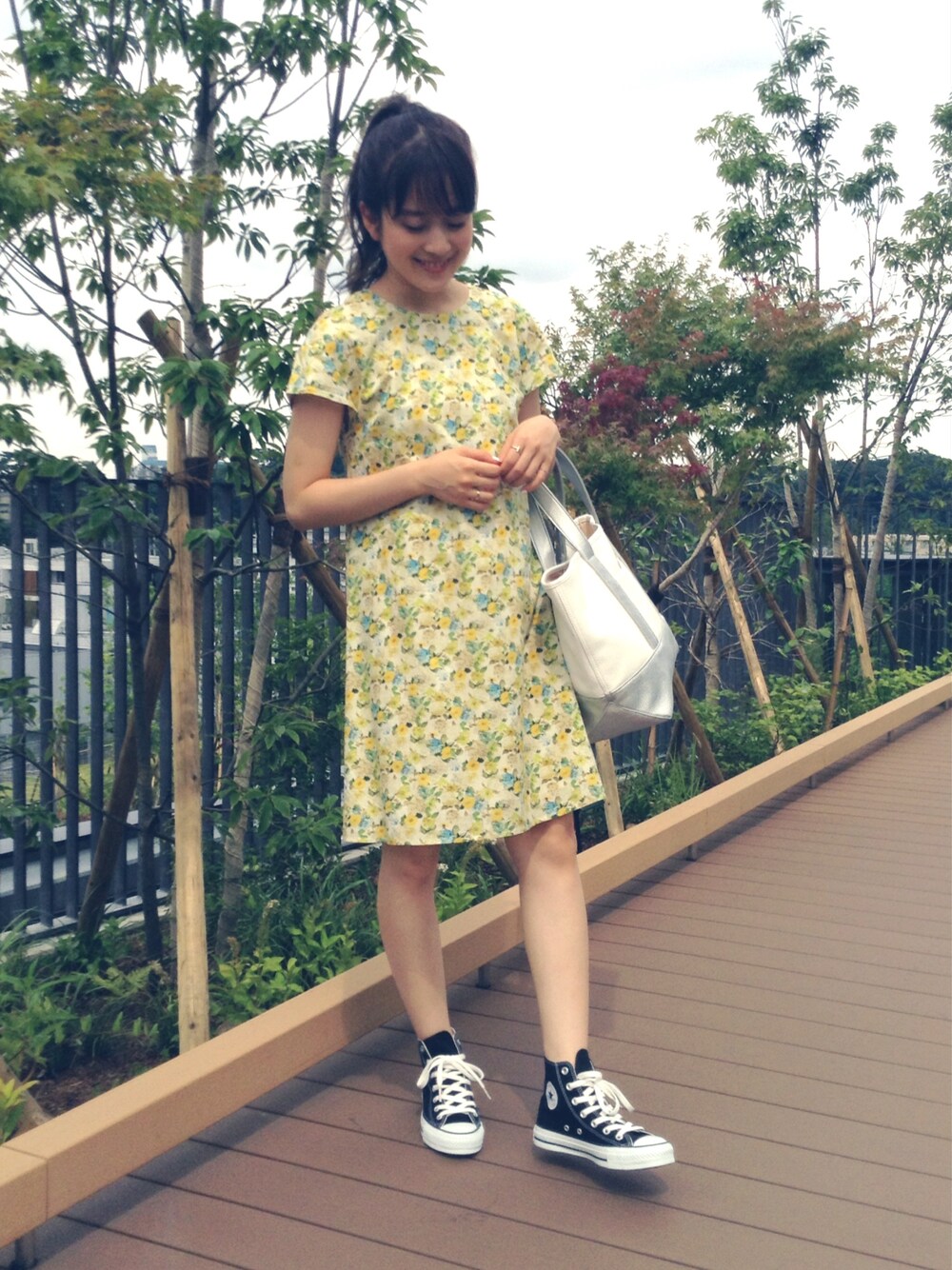 イエロー系のワンピース、ブラック系のスニーカーを着用したレディースの夏コーディネートの1枚目の写真