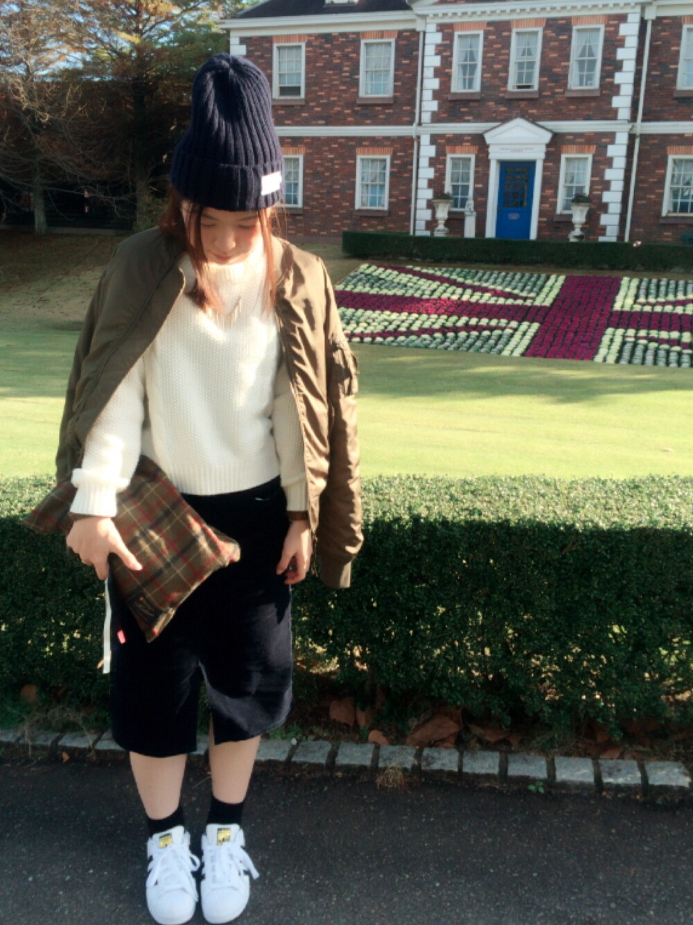 グリーン系のMA-1、ブルー系のスカート、ホワイト系のスニーカーを着用したレディースの秋コーディネートの1枚目の写真