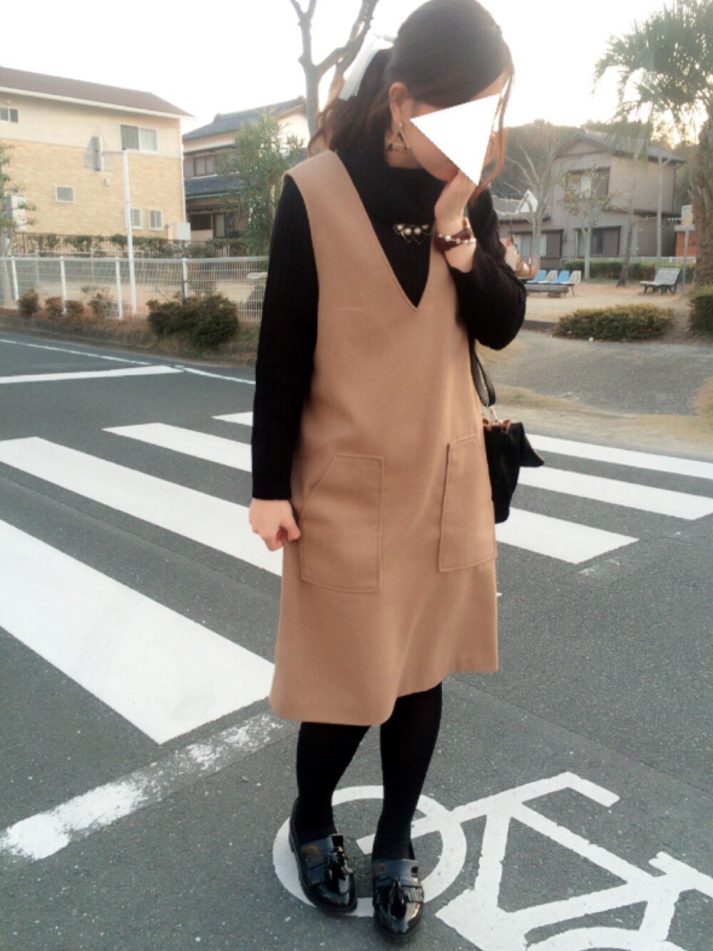 ブラック系のトップス、ベージュ系のジャンパースカート、ブラック系のローファーを着用したレディースの冬コーディネートの1枚目の写真